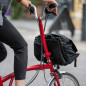 Preview: Im Anschnitt der Vorbau eines roten Brompton, eine Frau mit schwarze Hose und grauem Shirt hält den M Lenker.
