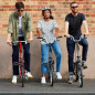 Preview: Drei Menschen sitzen jeweils auf einen Brompton Faltrad. Ein Mann auf einem S-Typ, in der Mitte eine Frau auf einem M-Typ und rechts ein Mann auf einem Faltrad mit H Lenker.