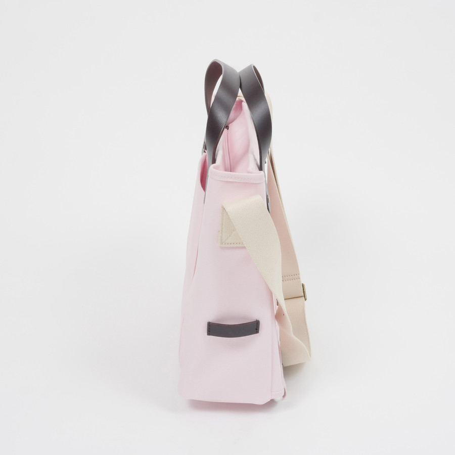 Die rosafarbige Brompton Tote Bag ist schräg von der Seite fotografiert, die weißen Schultergurte und die brauen Griffe sind gut sichtbar