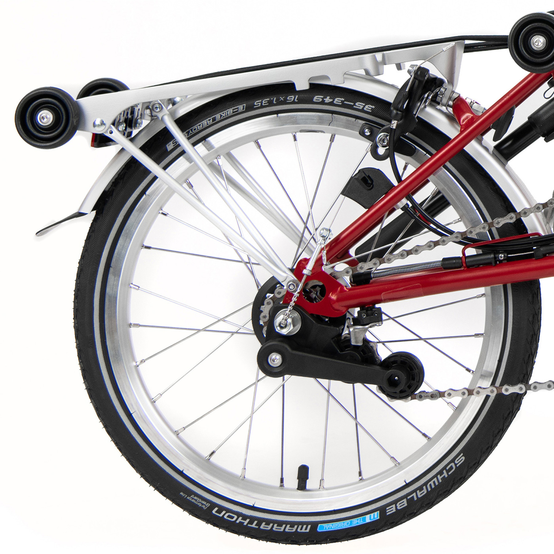 Das Hinterrad eines roten Brompton Faltrades ist mit Gepäckträger abgelichtet.